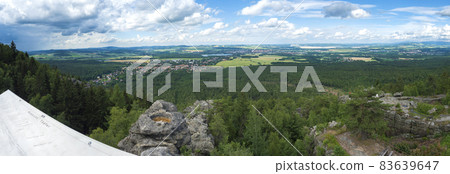 Panoramic view from hill Topfer sandstone viewpoint near Oybin with view of Zittau town at Poland German borders in Zittauer Gebirge mountains, Saxony, germany. Summer sunny day, blue sky, white 83639647