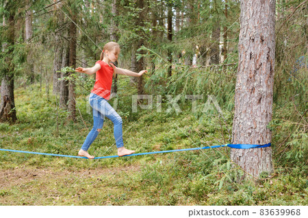 Girl balancing on slackline during summer holidays 83639968