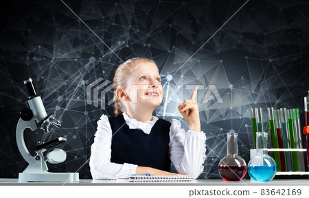 Little girl scientist sitting at desk 83642169