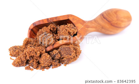 Muscovado sugar in wooden scoop, isolated on white background. Barbados sugar, khandsari or khand. 83642395