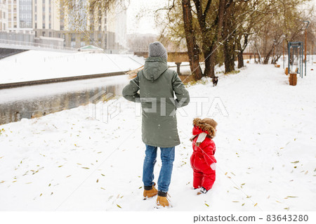 Unrecognizable young woman in winter casual outfit walking with her toddler kid 83643280