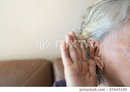 Hearing loss in seniors (Presbycusis) concept. Close up of elderly woman holding her hand near ear for trying hard to listen something. Elderly health care. Hearing loss in seniors (Presbycusis) concept. Close up of elderly woman holding her hand near ear for trying hard to listen something. Elderly health care. 83643289