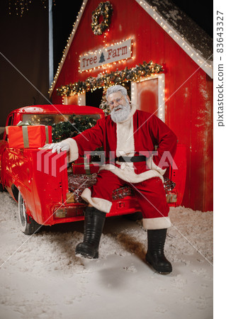 Portrait of Santa Claus with a car, a lot of gifts in the back. Preparing gifts for the celebration 83643327