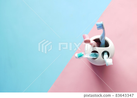 colorful toothbrushes in white mug against a wall colorful toothbrushes in white mug against a wall 83643347