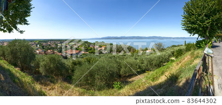 Castiglione del lago, Umbria, Italy. August 2020. Amazing landscape of the Trasimeno lakefront. From the top of the hill of the historic village the view is very wide. Large format panoramic photo. 83644302