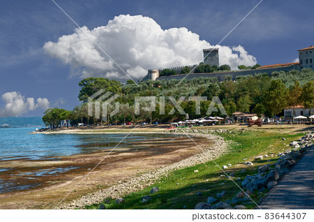 Castiglione del lago, Umbria, Italy. August 2020. Amazing landscape of the Trasimeno lakefront. In the background the historic village with the fort and the tower. Castiglione del lago, Umbria, Italy. August 2020. Amazing landscape of the Trasimeno lakefront. In the background the historic village with the fort and the tower. 83644307