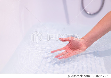 Woman checking a water temperature. Woman checking a water temperature. 83644726