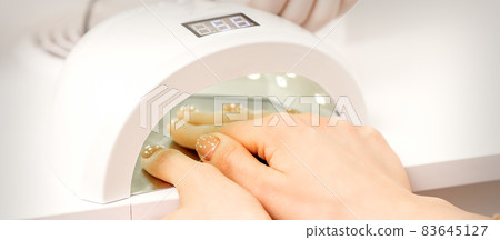 Female hand with manicured fingers dry inside UV light machine in manicure salon. Female hand with manicured fingers dry inside UV light machine in manicure salon. 83645127