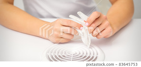 Beautician, doctor, or manicurist holds white latex protective gloves while preparing to wear them before providing services. Beautician, doctor, or manicurist holds white latex protective gloves while preparing to wear them before providing services. 83645753