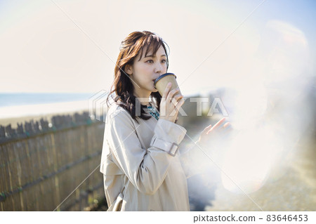 Woman drinking coffee at the beach Woman drinking coffee at the beach 83646453