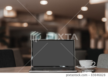 Mockup of laptop computer with empty screen with coffee cup and smartphone on table of the coffee shop background 83646828