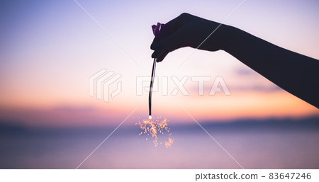 一個人在沙灘上做夏日傳統煙火的剪影 83647246