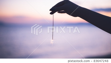 一個人在沙灘上做夏日傳統煙火的剪影 83647248
