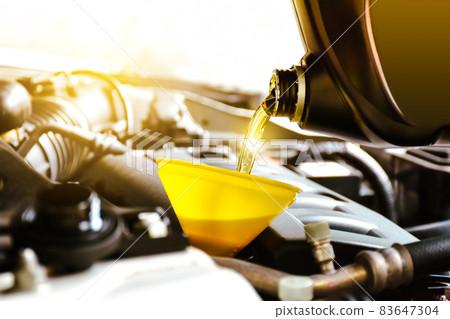 Mechanic pouring motor oil to engine in the repair garage shop 83647304