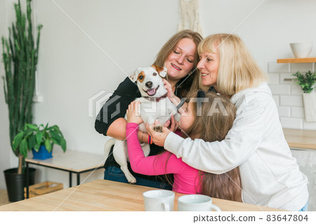 Happy granddaughter and grandmother and daughter having fun with jack russell terrier dog. Pet, family and three generation concept. 83647804
