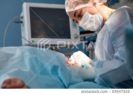 Close up of the face of a patient who is undergoing blepharoplasty. The surgeon cuts the eyelid and performs manipulations using medical instruments Close up of the face of a patient who is undergoing blepharoplasty. The surgeon cuts the eyelid and performs manipulations using medical instruments 83647826