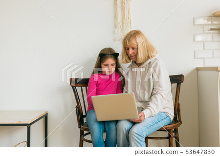 Child and granny using laptop in kitchen. Generation and family concept Child and granny using laptop in kitchen. Generation and family concept 83647830