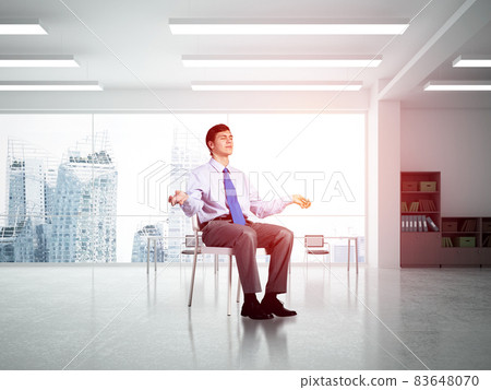 young businessman meditating in the office 83648070