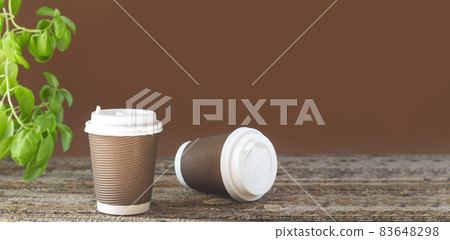 Banner takeaway paper coffee cup on table with green plant Banner takeaway paper coffee cup on table with green plant 83648298