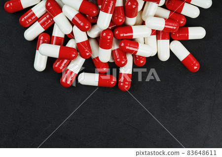 Pills with drugs are scattered on a black background 83648611