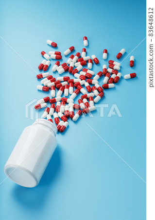 A scattering of white cans of Red and white ampoules with medicine and vitamins on a blue background. A scattering of white cans of Red and white ampoules with medicine and vitamins on a blue background. 83648612