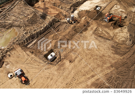 Laying a concrete well ring and sewer pipe at construction site. Laying a concrete well ring and sewer pipe at construction site. 83649926