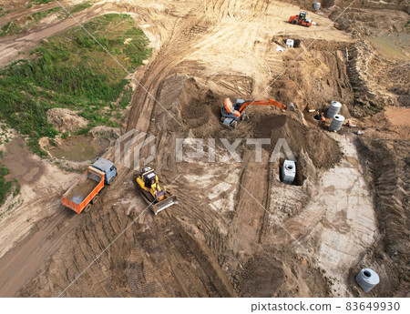Laying a concrete well ring and sewer pipe at construction site. Earthworks Laying a concrete well ring and sewer pipe at construction site. Earthworks 83649930