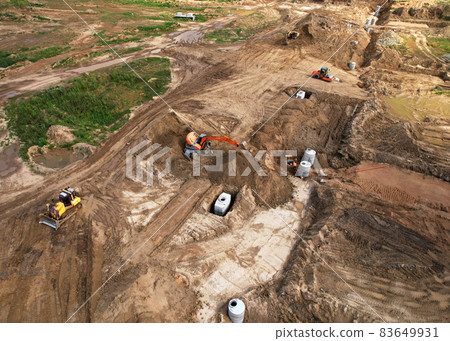 Laying a concrete well ring and sewer pipe at construction site. Earthworks Laying a concrete well ring and sewer pipe at construction site. Earthworks 83649931
