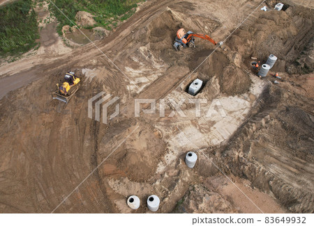 Laying a concrete well ring and sewer pipe at construction site. Earthworks Laying a concrete well ring and sewer pipe at construction site. Earthworks 83649932