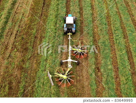 Tractor raking grass for silage harvesting. Tractor raking grass for silage harvesting. 83649993
