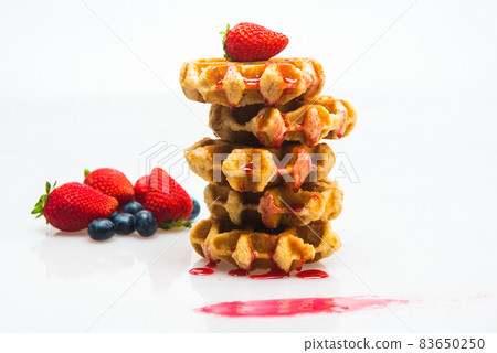 mountain of waffles with strawberry syrup on white background mountain of waffles with strawberry syrup on white background 83650250