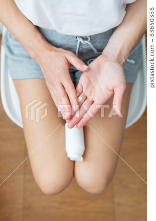 The girl holds a jar of bruise cream in her hands. The girl smears the cream on her hands. View from above. The girl holds a jar of bruise cream in her hands. The girl smears the cream on her hands. View from above. 83650338
