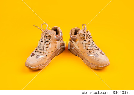 fashionable sportive sneakers with laces on yellow background, fashion 83650353