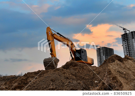 Excavator digging foundation at construction site.  83650925