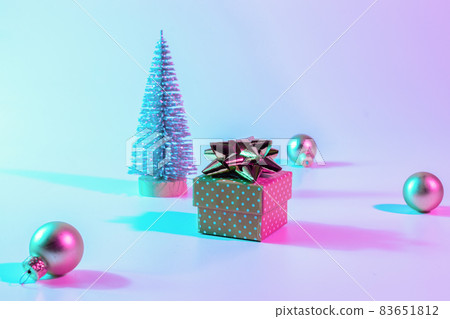 Christmas composition neon. Holiday decoration bauble ball on neon gradient backdrop. Minimal abstract tree, xmas gift box. New year banner. 83651812