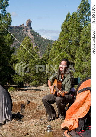 woman playing guitar among the pines woman playing guitar among the pines 83651976