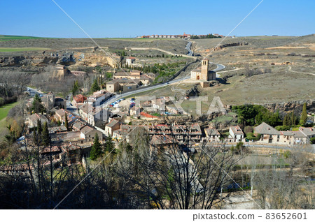 View of the Church of the Holy Sepulcher and the cityscape of Zamarramala on the slope from the Alcazar side of Segovia, Spain 83652601