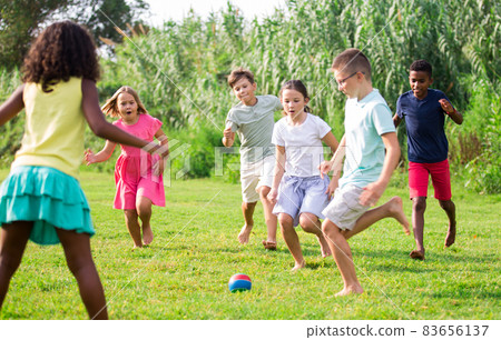 Kids running through grass and playing football 83656137
