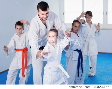 Young children doing karate kicks with male coach 83656166
