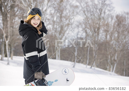 一名年輕女子站在滑雪板上看著相機滑雪板圖像 一名年輕女子站在滑雪板上看著相機滑雪板圖像 83656182