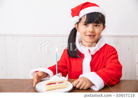 A child eating a Christmas cake, a girl dressed as Santa and chewing on a cake A child eating a Christmas cake, a girl dressed as Santa and chewing on a cake 83657118