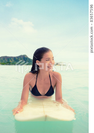 Surfer woman surfing on Waikiki Beach, Oahu, Hawaii. Female bikini girl on surfboard smiling happy living healthy active lifestyle on Hawaiian beach. Asian Caucasian model. Surfer woman surfing on Waikiki Beach, Oahu, Hawaii. Female bikini girl on surfboard smiling happy living healthy active lifestyle on Hawaiian beach. Asian Caucasian model. 83657596