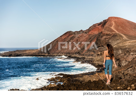 Mountain fitness model girl walking on trail path in volcanic rocks, outdoor adventure. Fit healthy active lifestyle person enjoying outdoors. 83657632