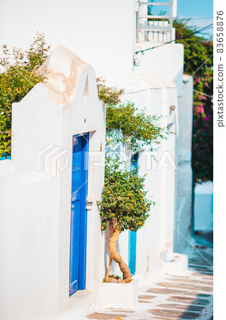 The narrow streets of the island with blue balconies, stairs and flowers in Greece. 83658876