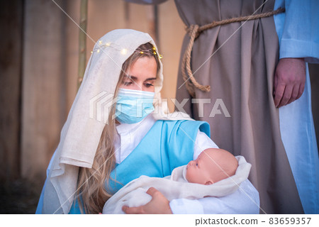woman with mask representing virgin mary holding Jesus baby 83659357