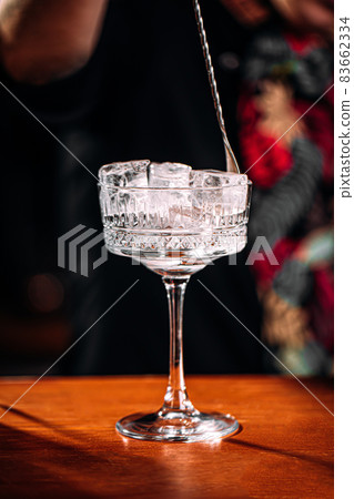 Bartender making cocktail with ice in fancy glass 83662334