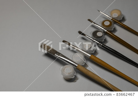 Paint containers and paint brushes against a gray background. Artist's Talent. 83662467