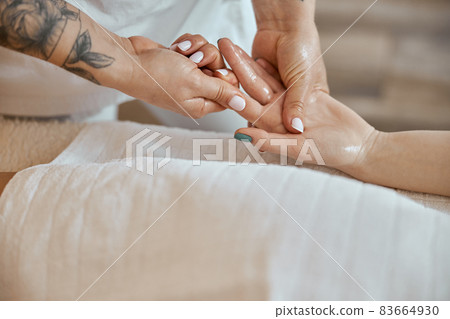 Professional confident massage master is doing procedures to caucasian woman in minimalistic modern cabinet Professional confident massage master is doing procedures to caucasian woman in minimalistic modern cabinet 83664930