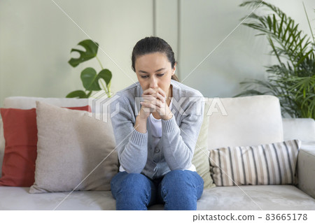 Depressed young woman on sofa at home. 83665178
