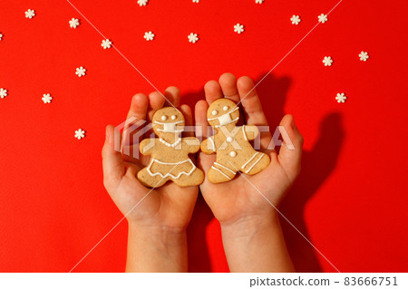 Happy 2022 New Year's set of cookies, gingerbread man, woman in face from ginger biscuits glazed sugar decoration in kids hands on red background, minimal seasonal pandemic winter holiday Happy 2022 New Year's set of cookies, gingerbread man, woman in face from ginger biscuits glazed sugar decoration in kids hands on red background, minimal seasonal pandemic winter holiday 83666751